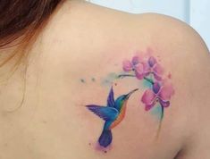 a woman's back shoulder with a hummingbird and flower tattoo on the left side