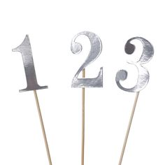 two silver cake toppers with the numbers twenty and three on sticks in front of them