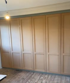 an empty room with wooden floors and closets on the wall, in front of a window