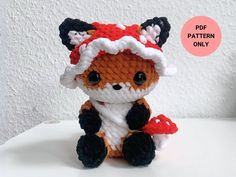 a small crocheted stuffed animal wearing a red and white hat with black ears