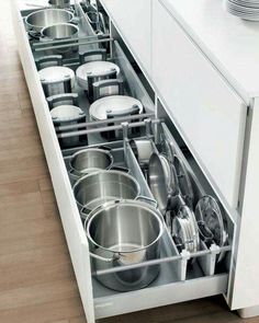 an open drawer in a kitchen filled with pots and pans