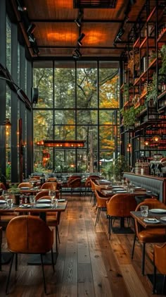 an empty restaurant with lots of tables and chairs in front of large glass windows that look out onto the woods