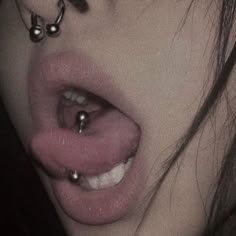 a woman's nose with piercings on it and her tongue sticking out to the side