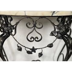 an ornate marble top table with wrought iron work