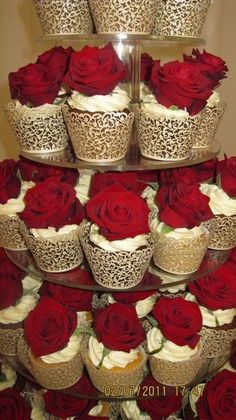 three tiered cake with red roses and lace on the top, surrounded by other cupcakes