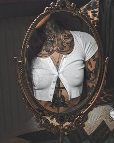 a woman's torso is shown in a mirror, with tattoos on her chest