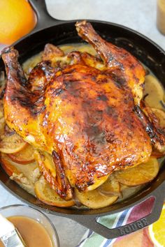 a whole chicken in a skillet with potatoes and oranges