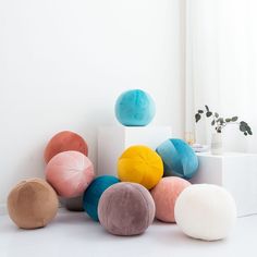 several different colored pillows sitting next to each other on a white surface in front of a window