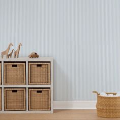 a toy giraffe and four baskets in front of a wall with blue stripes