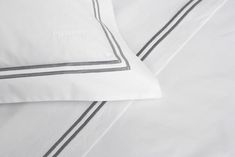 two pillows with black and white trims are on top of each other in this bedding set