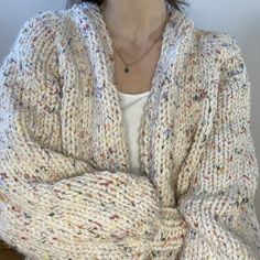 a woman with her arms crossed wearing a sweater