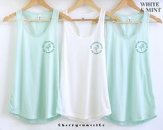 three women's tank tops hanging up against a wall with the words white and mint on them