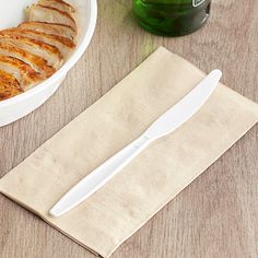 a plate with slices of chicken next to a bowl and knife on a table top