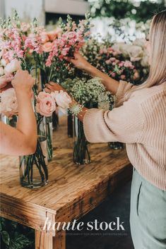 two women arranging flowers in vases on a table