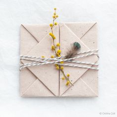 a piece of paper tied up with twine and some yellow flowers on top of it