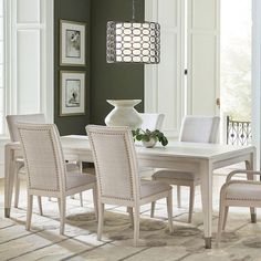 a dining room table with white chairs and a chandelier hanging from the ceiling