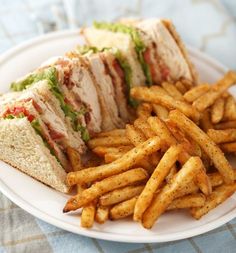 a white plate topped with a cut in half sandwich and french fries