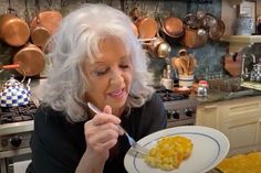 an older woman holding a fork and looking at the food she has on her plate