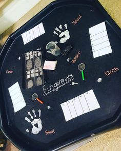 a black tray with handprints and other items on it, sitting on a table