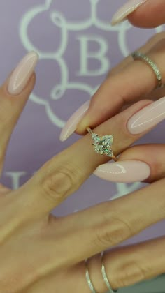 a woman's hands with pink manicures and rings on them, holding onto her nails