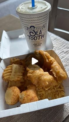 an open takeout box with fried food and a drink