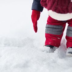 a person walking in the snow wearing red and grey ski pants with matching mittens