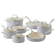 a set of white pots and pans with lids on top of each one,