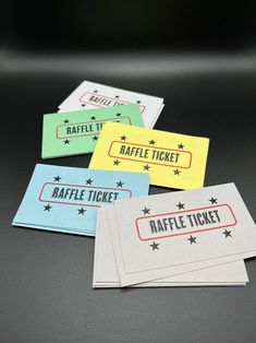 four raffle ticket cards sitting on top of a black table next to each other