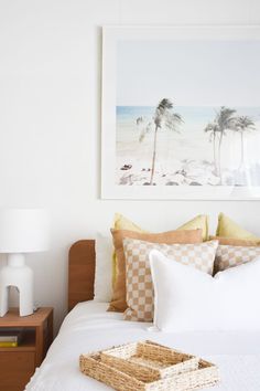 a bed with white sheets and pillows on top of it next to a framed painting