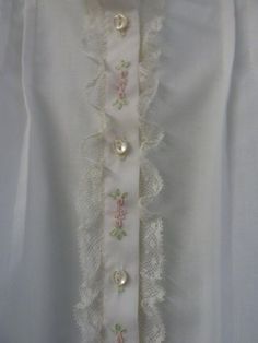 a white shirt with buttons and lace on it