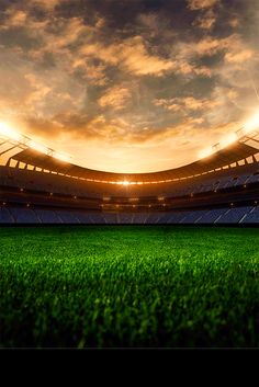 an empty soccer stadium with the sun shining down on it and green grass in front