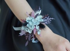 a close up of a person's wrist wearing a flower and feather corsage