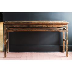 an old wooden bench sitting on top of a hard wood floor next to a wall