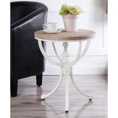 a white table with a potted plant on top and a black chair in the background