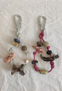 two key chains with charms attached to them on a white cloth covered tablecloth,