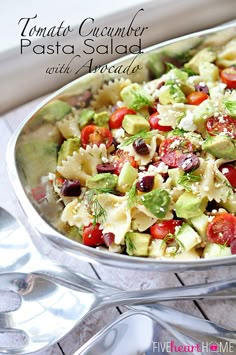 a pasta salad with tomatoes, avocado and feta cheese in a serving dish