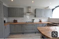 a kitchen with grey cabinets and wooden counter tops