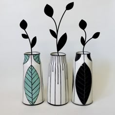 three black and white vases with plants in them