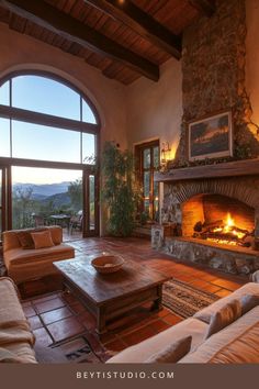 a living room filled with furniture and a fire place in front of a large window