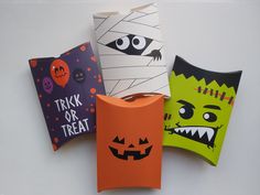 four halloween paper bags with faces and mouths on them, all decorated in different colors