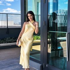 a woman in a yellow dress is posing for the camera with her hand on her hip