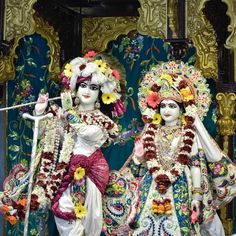 two statues of women dressed in colorful clothing with flowers on their heads and arms, standing next to each other