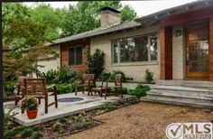 a patio with chairs and potted plants in front of a house