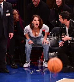 a woman sitting on top of a chair in front of a basketball while people watch