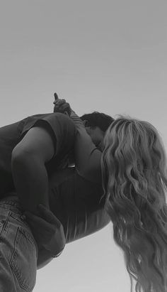 black and white photograph of a person kissing another person's head with the sky in the background