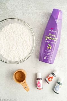 ingredients to make homemade vanilla ice cream laid out on a white counter top, including an empty glass bowl and wooden spoon