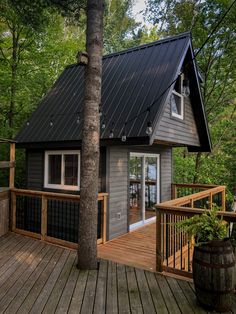 a small cabin in the woods with a deck and railings on it's side