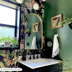 a bathroom with green walls and wallpaper has a mirror, sink, and plants