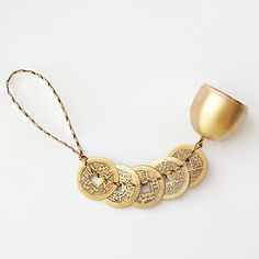 a gold necklace with five coins on it and a golden cup in the back ground