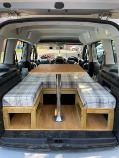 the back end of a van with two seats and a table in the trunk area